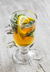 green tea with lemon and a rumpled in a glass mug on a light wooden background