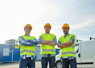 happy male builders in high visible vests outdoors