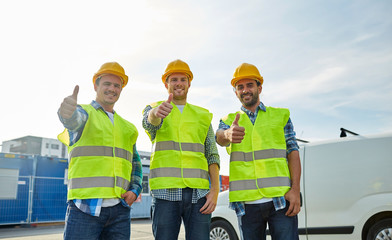 happy male builders in high visible vests outdoors