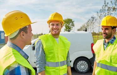 happy male builders in high visible vests outdoors