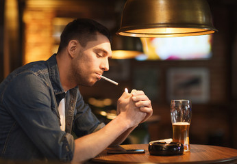 man drinking beer and smoking cigarette at bar