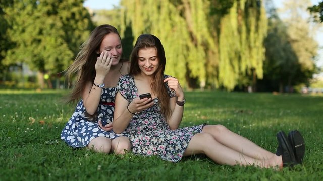 Two young girls sitting on a nature shoot selfies and having fun.