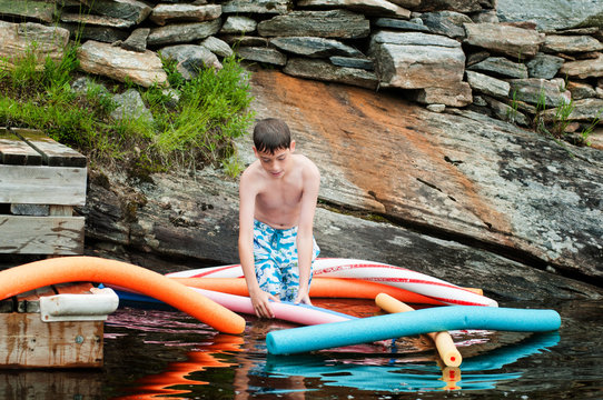 child in a lake in Muskoka region ontario canda floating on pool noodles