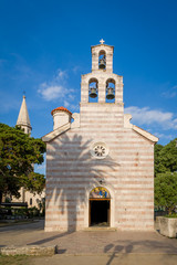 Fototapeta na wymiar Old church with high bell tower in Budva