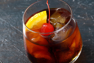 long drink con ghiaccio ciliegia e arancio bicchiere su sfondo scuro