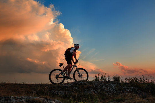 Silhouette of a biker and bicycle on sky background.