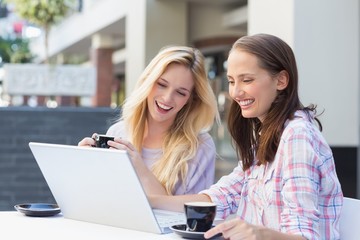 Happy women friends looking at laptop