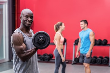 Smiling muscular man lifting a dumbbell 