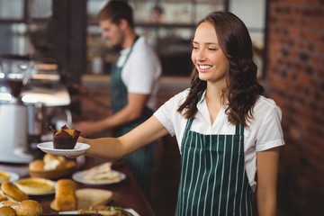Smiling waitress serving a muffin
