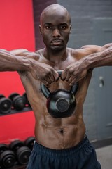 Fototapeta na wymiar Portrait of muscular man lifting a kettlebell