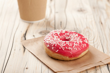 Donut and paper cup on wooden table