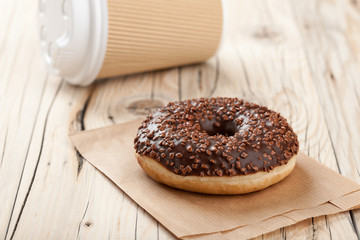 Donut and paper cup on wooden table