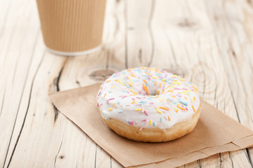 Donut and paper cup on wooden table