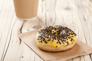 Donut and paper cup on wooden table