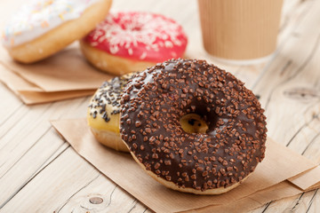 Colorful donuts and paper cup on wooden table