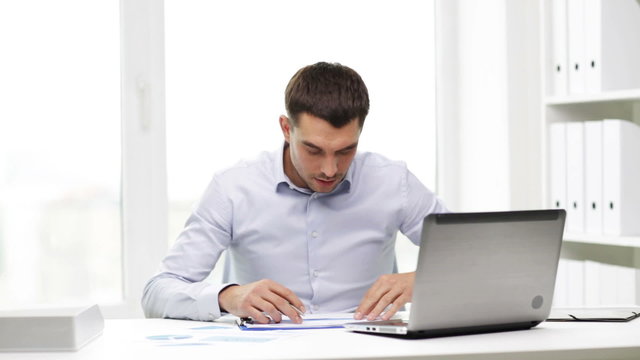 busy businessman with laptop and papers in office