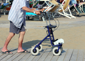 Fototapeta na wymiar senior man walking with Walker on the beach in summer