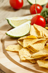 Nachos, tomato sauce, tomatoes, greens, lime on a wooden table,