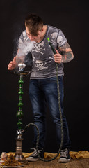 Tattooed man smoking traditional hookah.