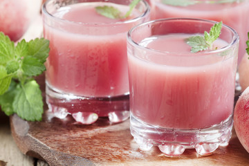 Freshly squeezed pink peach juice in glasses, selective focus
