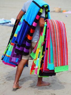 African peddler of towels and beach towels on the beach in summe