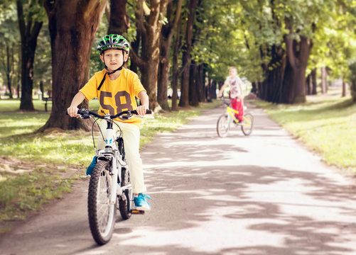 Two boys ride a bicycle in park