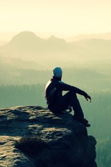 Hiker sits on a rocky peak and enjoy the mountains scenery