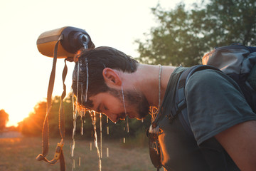Hiker dropping fresh water on his head 