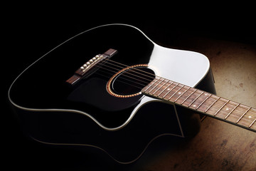 Black acoustic guitar with light reflection