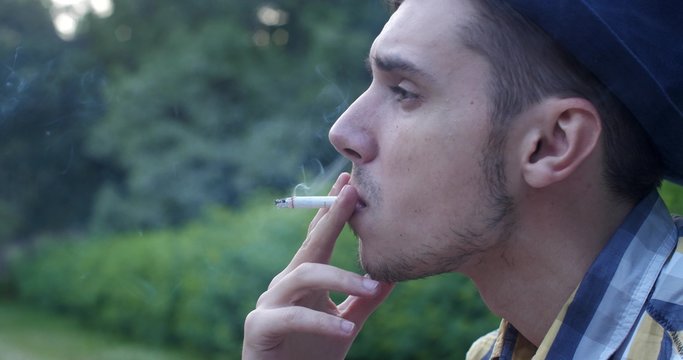 Hipster guy smoking in the park