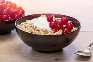 black bowl of cereals, redcurrants and yogurt