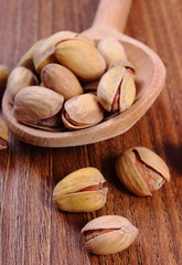 Pistachio nuts with spoon on wooden table, healthy eating