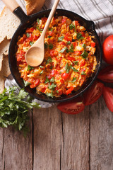 Menemen in a pan and ingredients on the table. vertical top view
