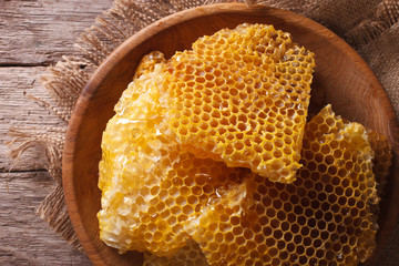 Golden honeycombs on a wooden plate. Horizontal top view closeup
 - obrazy, fototapety, plakaty