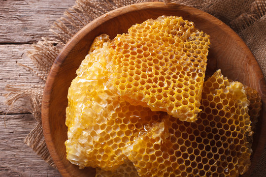 Golden honeycombs on a wooden plate. Horizontal top view closeup
