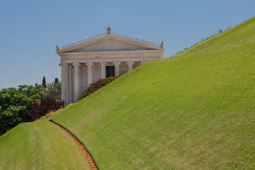 Fototapeta na wymiar Greek building behind green grass slope, Bahai gardens, Israel