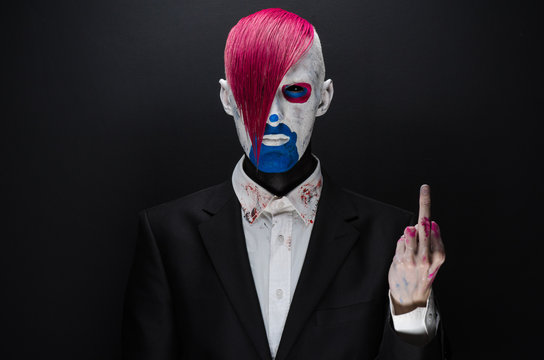 Clown and Halloween theme: Scary clown with pink hair in a black jacket on a dark background in the studio