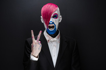 Clown and Halloween theme: Scary clown with pink hair in a black jacket on a dark background in the...