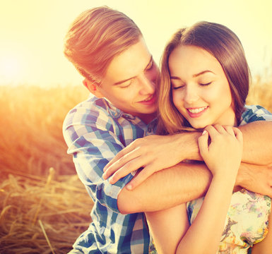 Happy couple kissing and hugging outdoors on wheat field, love concept
