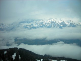 Panoramic snowy winter landscape in the Austrian Alps on a cloudy day, with mountain tops covered with fog.