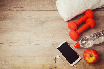 Fitness background with bottle of water, dumbbells and smartphone. View from above