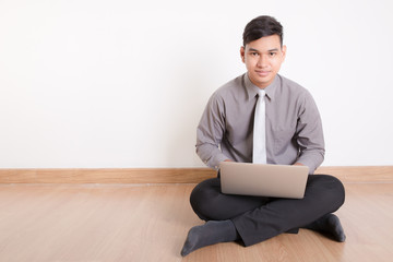 Young businessman sitting on the floor and typing on a laptop