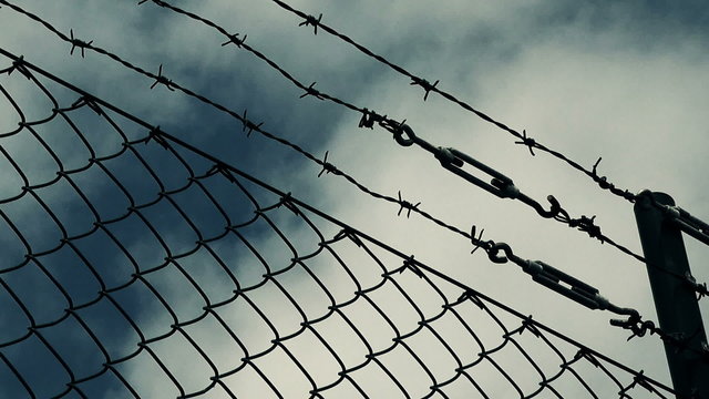 Barb wire fence and clouds, dreaming of freedom concept, time lapse footage