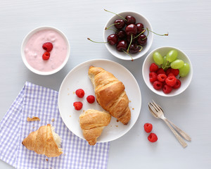 Frühstück mit Croissant, Joghurt und Beeren