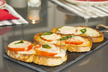 Basil tomato and cheese bruschetta over a slate rock board