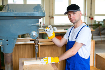 worker in a carpenter's workshop using drilling machine