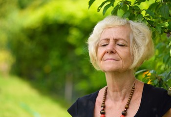 Mature, blonde woman in garden,