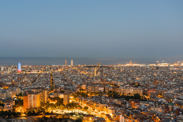 Fototapeta na wymiar Top view and night photography of an illuminated Barcelona. The panorama shows the famous Sagrada Familia, the illuminated Torre Agbar and the Towers of the Port Olimpic until the harbor