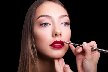 Obraz premium close portrait of beautiful girl making make up. Isolated on black background. Copy space.