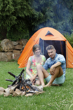 Attraktives junges Pärchen am Lagerfeuer beim Camping